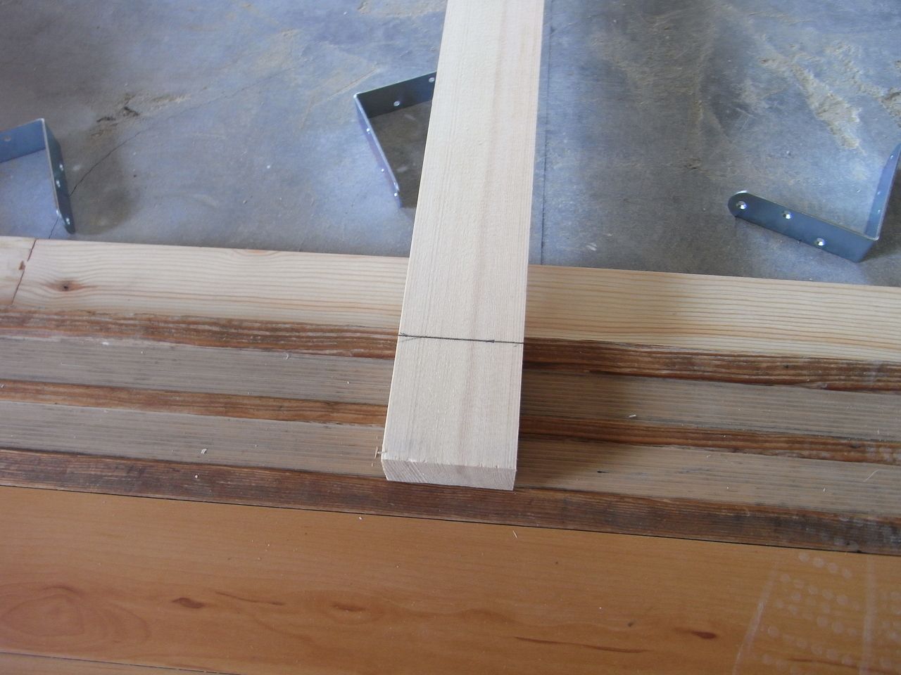 壁際の根太材を壁際から少し内側に入れるので、一文字プレートでジョイントさせた根太材の長さが原状のままでは少し長くなってしまいます。
そこで余分な部分を丸ノコでカットしていきます。
ちなみに、上の写真の一番左側に写っているＬ型の道具は「差し金（さしがね）」です。
この道具一つで木材に直角の線を引くだけでなく、木材の幅を測らなくても等分割できたりと色々な使い方ができてとても役に立つ道具です。