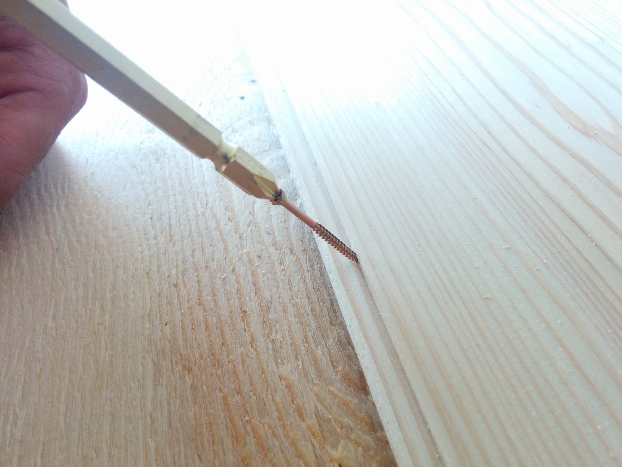 フロアー用ビスで固定する サネと呼ばれる部分にフロアー用ビスを打ち込みます。
フロアー釘を使って固定するのもいいのですが、インパクトドライバーがあるならフロアー用ビスを用いて固定するのが楽です。
この作業のポイントとしては、サネに対してビスを45°の角度で打ち込み、ビスの頭は沈めるようにします。